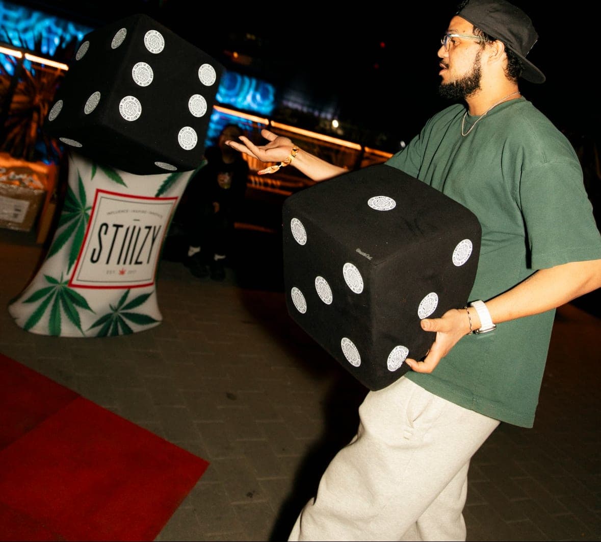 Staffer running a giant-dice game beside a branded STIIZY inflatable
