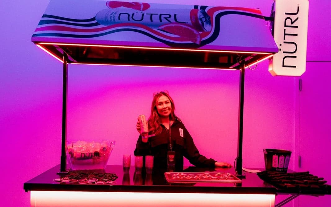 Staffer holding a NUTRL can at the branded NUTRL bar cart